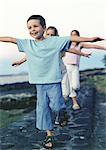 Children walking single file with arms out