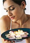 Woman holding plate of aromatic candles and rose petals, looking down, close-up