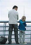 L'homme et fils de pêche sur la jetée, vue arrière