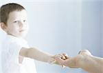 Boy reaching out to touch adult's hand