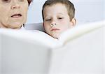 Grandmother reading book to boy