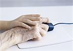 Child's hand and elderly man's hand on computer mouse