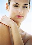 Woman with arm across chest, looking at camera, close-up