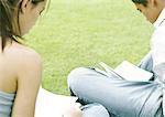 Students sitting on grass studying, rear view