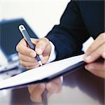 Businessman signing document at desk, close-up of hands