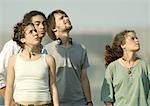 Four young friends standing, looking up at sky