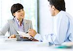 Businessman speaking to businesswoman and holding document