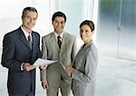 Three business associates standing in lobby, smiling