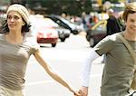 Young couple holding hands in busy street