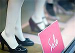 Sale sign by mannequins' feet in shop window