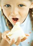 Girl eating piece of cake with hand