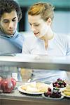 Young adults in exercise clothing having snack in health club cafeteria