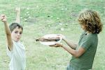 Boy handing friend plate of grilled meat