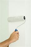 Man painting wall with paint roller, cropped view of hand