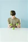 Teen boy holding up comparing three apples