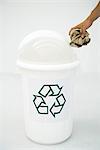 Man's hand placing cardboard in recycling bin, cropped