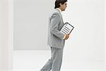 Businessman walking, carrying document, side view