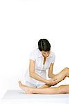 Femme donnant le massage de jambe, brandissant une jambe, recadrée vue des jambes