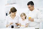 Parents and young daughter preparing breakfast in kitchen