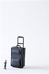 Miniature businessman facing large suitcase