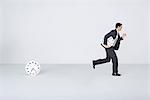Businessman running with clock, leaving second clock behind