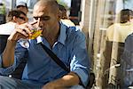 Man drinking a beer at a sidewalk cafe