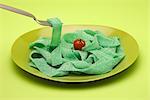 Food concept, plate of green gummy candy arranged like pasta, topped with cherry tomato