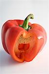 Red bell pepper with section cut out revealing tiny white seeds within