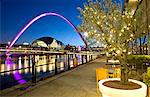 Blick entlang der Newcastle Quayside in der Nacht am Fluss Tyne, das Flutlicht Gateshead Millennium Bridge und die Sage Gateshead, Newcastle upon Tyne, Tyne and Wear, England, Vereinigtes Königreich, Europa