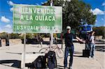Hitchhiker at the border of Bolivia and Argentina, sign showing 5121km to Ushuaia at the bottom on Argentina, Argentina, South America