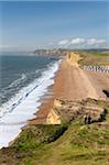 Two walkers enjoy the view along the beautiful vista from the cliffs of Burton Bradstock, looking towards East Cliff, West Bay and Golden Cap, Dorset, England, United Kingdom, Europe