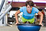 Femme faire des pompes avec boule d'équilibrage dans le gymnase