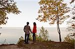 Backview of Young Couple Standing at Edge of Cliff Looking out at View, Ontario, Canada
