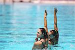 Schwimmer mit Arm erhoben, synchronisierte Schwimmen