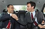 Businessmen shaking hands in car