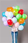 Woman holding large amount of balloons