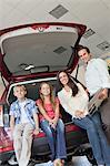 Portrait of happy family sitting at back of their new car