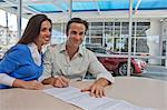 Couple de signer des documents pour voiture neuve