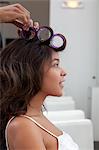 Side profile of young woman wearing curlers