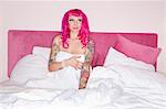 Woman in pink wig sitting in bed