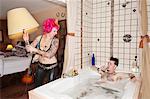 Pink haired woman throwing lamp on man in the bathtub