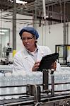 Man at bottling plant inspecting bottled water on conveyor