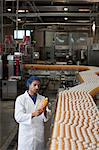 Worker inspecting orange juice bottle at bottling plant