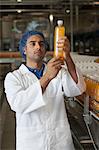 Factory worker examining orange juice bottle