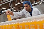 Worker checking juice bottle on production line