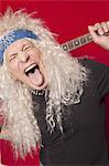 Nahaufnahme des mittleren Alters männlichen Gitarristen ragte Zunge über farbigen Hintergrund