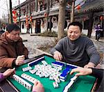 Chinese men playing traditional game of mahjong in a hotel courtyard decorated with red lanterns during Chinese New Year, Chengdu, Sichuan, China, Asia