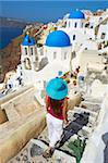 Tourist and church with blue dome, Oia (Ia) village, Santorini, Cyclades, Greek Islands, Greece, Europe