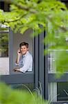 Businessman using cell phone in window