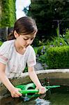 Girl filling up watering can in fountain